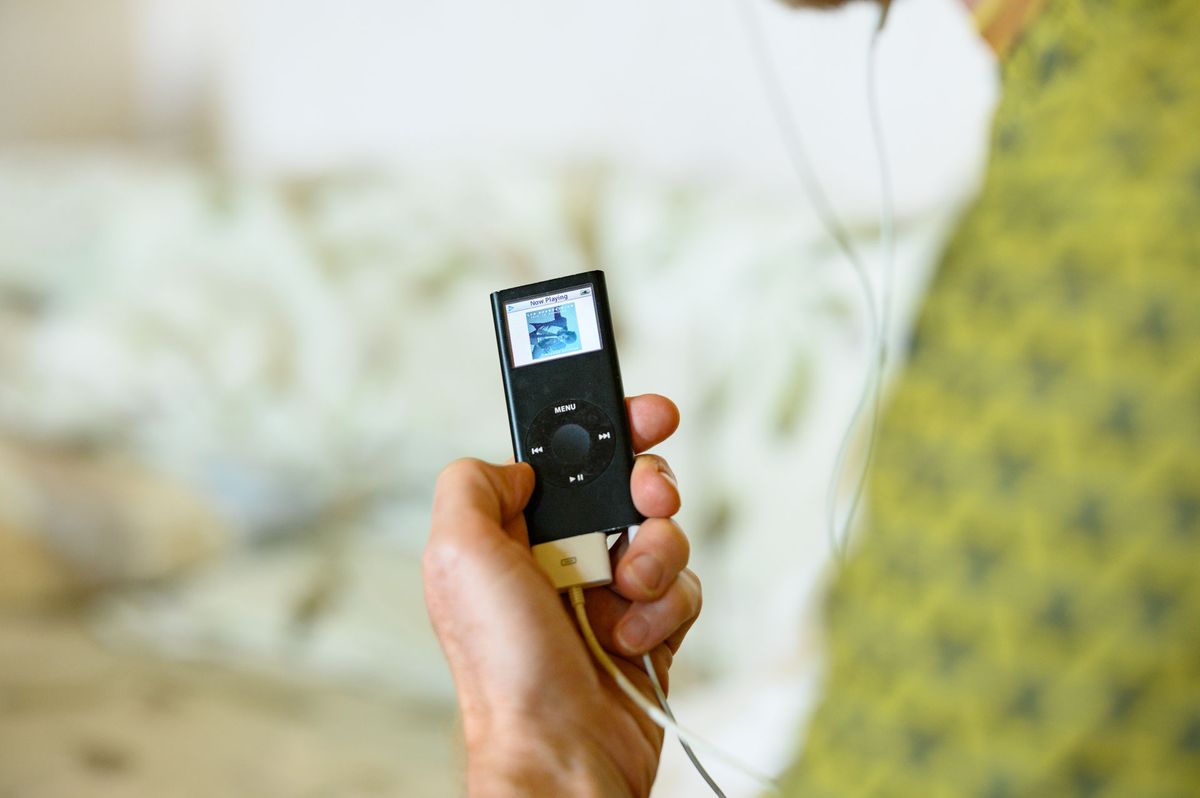 Black iPod Nano 2006 8GB model in person's hand, music artwork on the screen