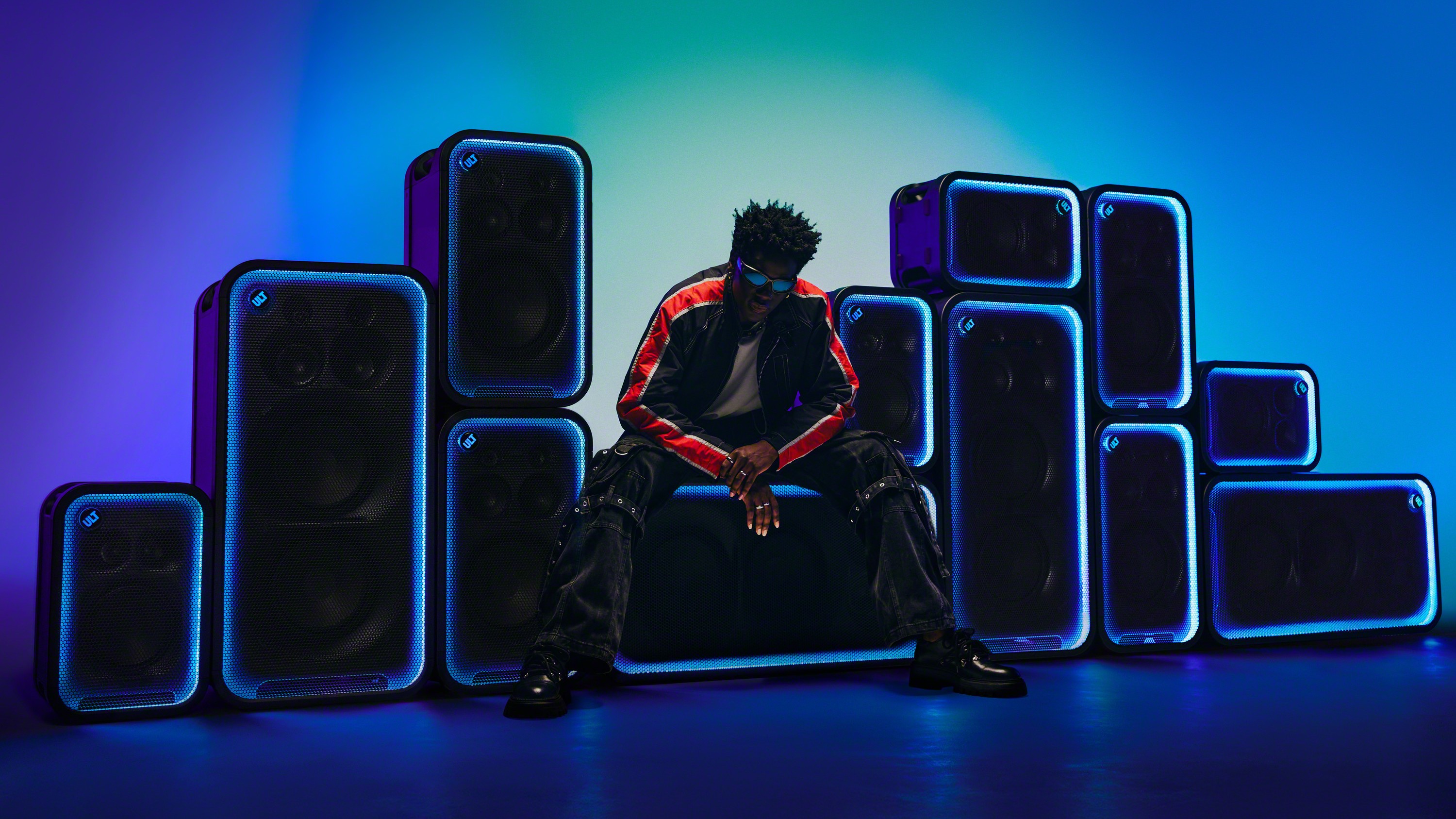 Man sat on Sony ULT Tower speaker surrounded by other ULT Tower 5, 7, and Max models